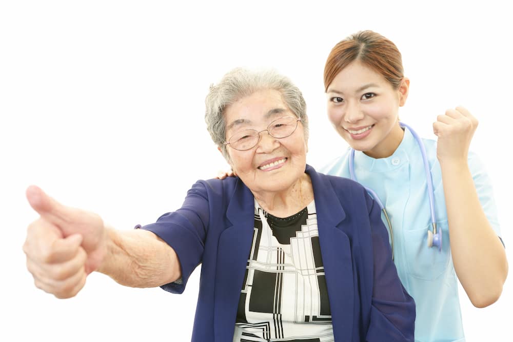 笑い合う高齢の女性と看護師